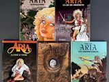 four books of comics are lined up on a gray surface