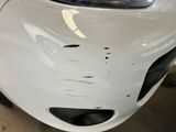 a white car that has been dented and is in a garage