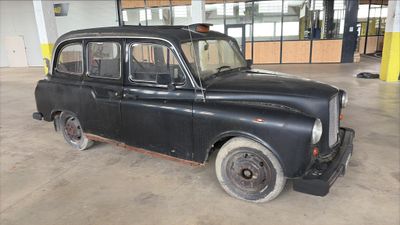 an old black car that is parked in a garage