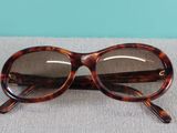 brown tortoise frame sunglasses with clear lens lenses on a gray surface