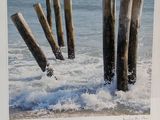 a picture of a picture of a beach with wooden posts sticking out of the water