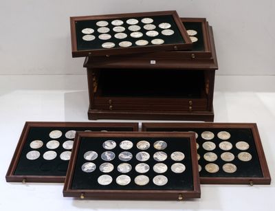 trois boîtes en bois contenant des pièces d'argent, posées sur une surface blanche