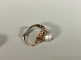 a gold ring with a pearl in it on a white surface
