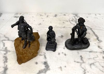 trois figurines représentant des hommes assis sur un rocher