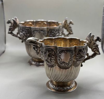 two silver vases sitting on top of a table next to each other