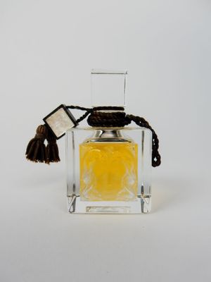 une image représentant un flacon de parfum posé sur une surface blanche