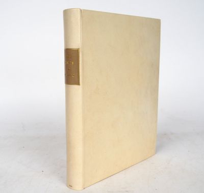 an old book with a gold cover sitting on a white surface