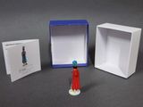 a small figurine of a woman in a red dress next to a box