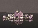 broche composée d’un amethorate violet et de perles d’amethorate, sur un fond noir