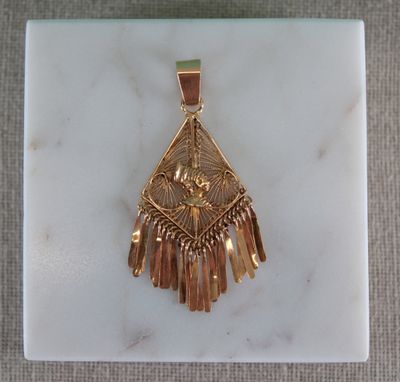 un gros plan d'un pendentif en or posé sur une surface en marbre