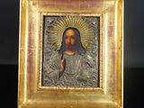 une image représentant un portrait de Jésus dans un cadre doré posé sur une table