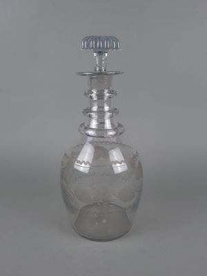 une bouteille en verre transparent avec un bouchon argenté, posée sur une surface grise