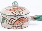 a small pot with a lid that has a fish design on it