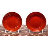 une paire d'assiettes rouges posées sur une table en marbre, sur fond blanc