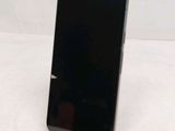 the back of a black cell phone sitting on top of a wooden stand