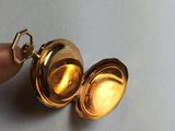 a small gold pocket watch with a key in it