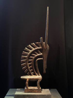 une sculpture en bronze représentant un cheval sur un socle, avec un fond noir