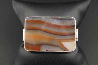 une bague en argent sertie d'une pierre rayée de brun et d'orange