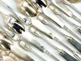a lot of spoons and spoon knives on the table