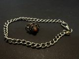 a close up of a silver chain with a red bead on it
