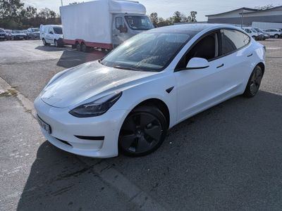 the white tesla model 3 is parked in a parking lot