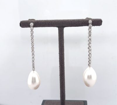 a pair of pearl and diamond earrings on a stand