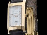a gold wrist watch with a black leather band