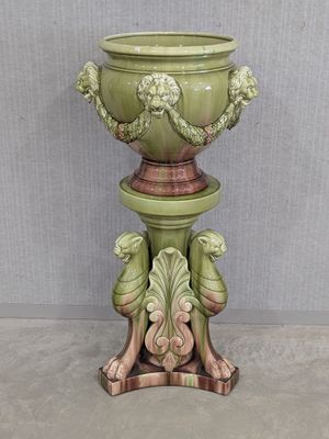 a green vase on a pedestal with a bird on it