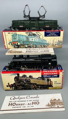 trois trains miniatures dans leurs boîtes, empilés les uns sur les autres sur une table