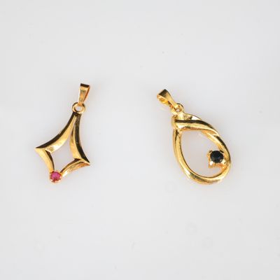 deux pendentifs en or sertis d'un diamant noir et d'une pierre rouge