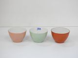 trois bols de couleurs différentes sont alignés sur une surface blanche