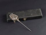 un gros plan d'une broche en métal ornée d'une fleur