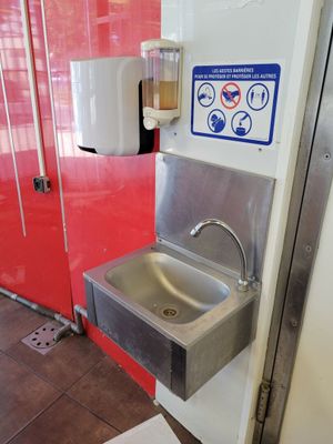 a stainless steel sink in the corner of a public restroom