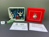 an image of a box with a miniature figurine of a woman in a red dress