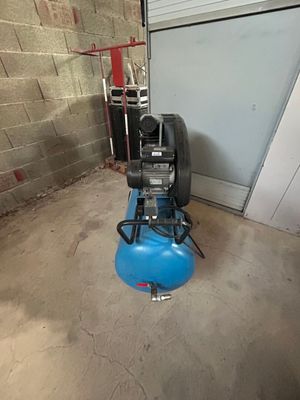 un compresseur d'air bleu posé sur le sol d'un garage