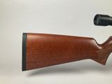 a rifle with a wooden stock and a scope on a white background