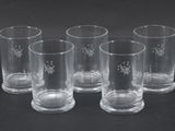 six verres transparents décorés, posés sur un fond noir