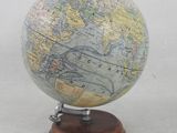 un petit globe terrestre posé sur un socle en bois et orné d'une carte