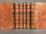 four old books are lined up in a row on a table