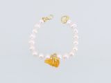 un bracelet de perles blanches orné d'une breloque en forme de papillon doré