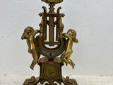 a gold clock on a stand on a white surface