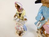 two figurines of a man and a woman with a bird on their head