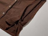 a brown shirt sitting on top of a white table next to a pair of scissors