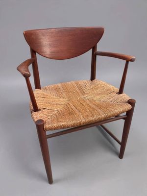 a wooden chair with a woven seat on a grey background
