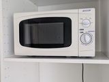 un micro-ondes posé sur une étagère dans un coin de la pièce