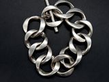a close up of a silver bracelet on a black surface