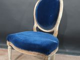 a blue chair with a wooden frame and a blue velvet upholstered seat