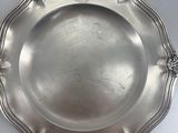 an antique silver plate on a white table with a silver handle