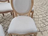 four white chairs sitting on top of a brick patio next to a potted plant
