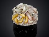 a close up of a white and yellow flower ring on a black surface
